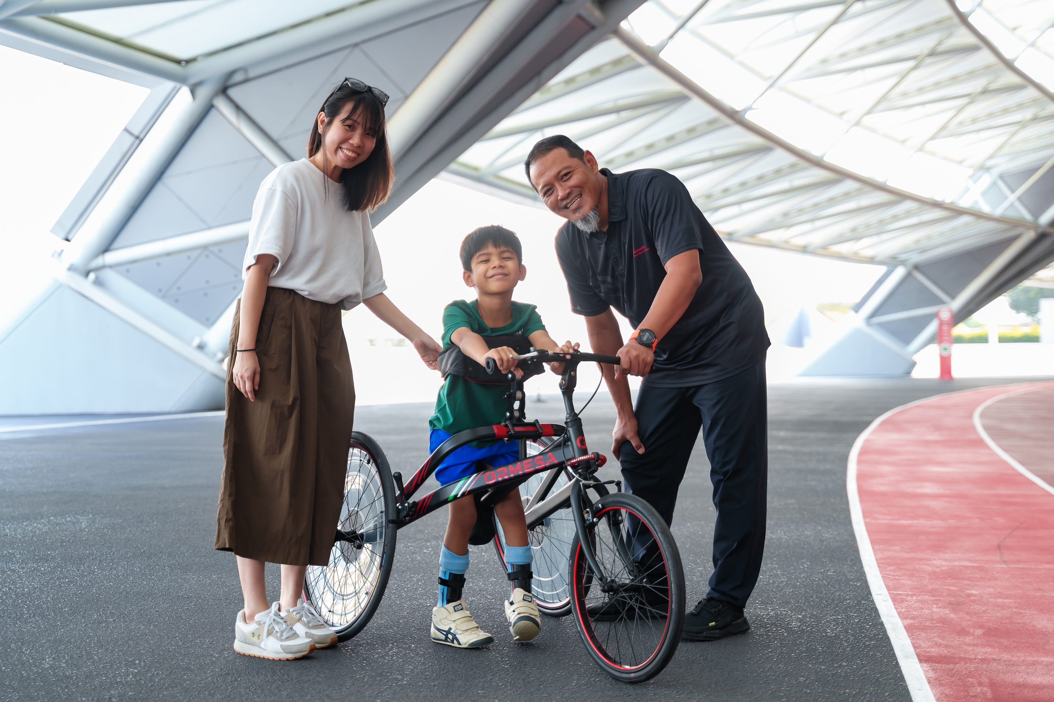 A older woman standing next to a young boy holding his frame running equipment and an older man standing on the right.